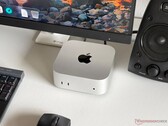 En Apple M6 Mac mini på ett skrivbord i en speluppsättning med skärm, tangentbord, mus och högtalare.