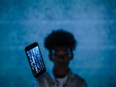 Svävande smartphone med kod på skärmen framför en blå bakgrund, med en suddig person bakom den