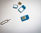 SIM-kort i tre storlekar och en utmatningsnål på en vit yta
