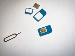SIM-kort i tre storlekar och en utmatningsnål på en vit yta