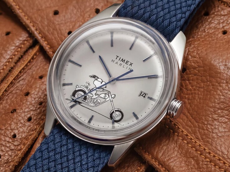 Vinklad framifrånvy av Peanuts x Timex Marlin Jet Automatic Easy Rider som visar det välvda glaset, det silverfärgade rostfria stålboettet, urtavlan med Snoopy-motiv och det blå tygarmbandet.