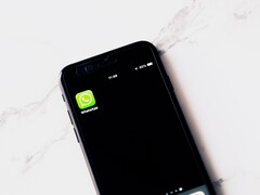 En smartphone på ett vitt bord där WhatsApp-appen visas