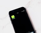 En smartphone på ett vitt bord där WhatsApp-appen visas