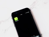 En smartphone på ett vitt bord där WhatsApp-appen visas