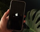 En hand håller en iPhone, Apples logotyp och en förloppsindikator lyser på skärmen.