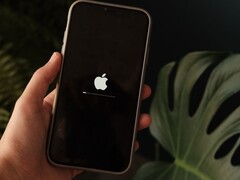 En hand håller en iPhone, Apples logotyp och en förloppsindikator lyser på skärmen.