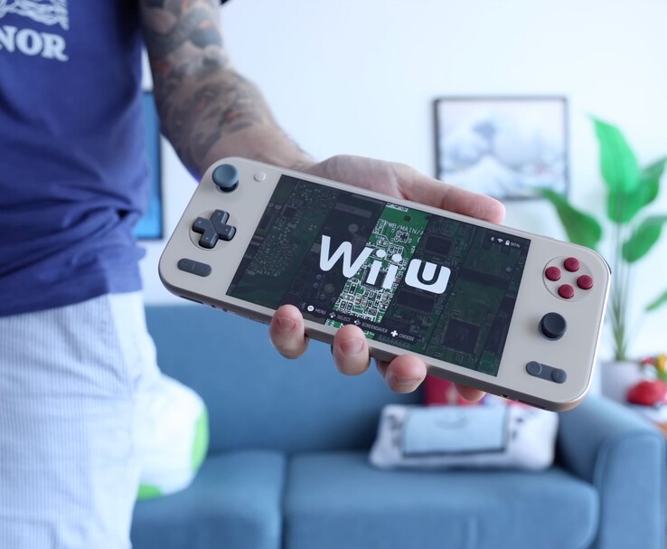Russ från Retro Game Corps håller i den handhållna konsolen Ayaneo Pocket S2 som kör en Wii U-emulator, med enheten väl synlig i ett vardagsrum. (Bildkälla: Retro Game Corps)