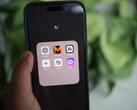 En hand håller en smartphone som visar en mapp med namnet AI med appar som Gemini, ChatGPT och Claude