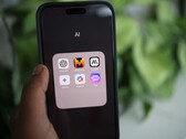 En hand håller en smartphone som visar en mapp med namnet AI med appar som Gemini, ChatGPT och Claude