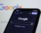 Smartphone som visar Googles söksida framför en skärm med Googles logotyp