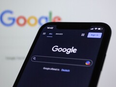Smartphone som visar Googles söksida framför en skärm med Googles logotyp