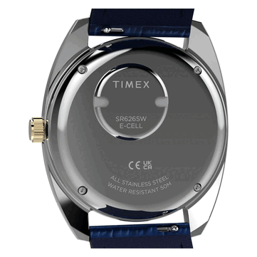 Baksidan av den guldfärgade Timex Q 1976 Day and Date, som visar dess boettlock i rostfritt stål, batterifack och märkning för 50 meters vattentålighet.