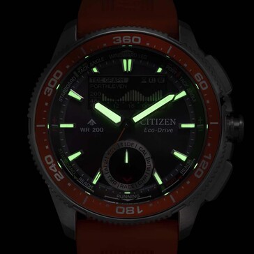 Lymdbild i svagt ljus av Citizen Promaster Wave Tracker JV3000-13E med lysande visare och timmarkörer mot en mörk bakgrund.