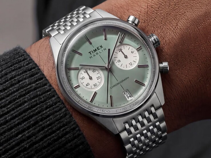 En Timex Marlin Jet Chronograph med en salviagrön urtavla och ett armband i rostfritt stål bärs på handleden och visar sitt välvda glas och den rundade retrofuturistiska boettprofilen.