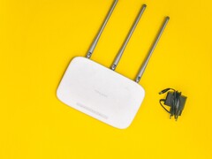 Vit Wi-Fi-router med tre antenner och en strömförsörjning på gul bakgrund