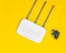 Vit Wi-Fi-router med tre antenner och en strömförsörjning på gul bakgrund