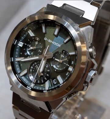 Närbild på Casio G-Shock GST-W1000D-3A med grön urtavla, som visar dess geometriskt strukturerade urtavla, tre hjälputtavlor, självlysande markörer och en polerad bezel i rostfritt stål.