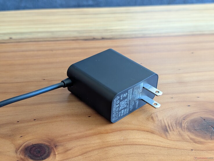 En 65 W USB-C-nätadapter som medföljer Lenovo Yoga Slim 7 14. Lägg märke till de icke-infällbara nätkontakterna och den inbyggda USB-C-kabeln i den andra änden