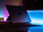 En halvöppen MacBook i ett mörkt rum, där ljus strömmar ut genom springan och faller på skrivbordet