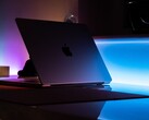 En halvöppen MacBook i ett mörkt rum, där ljus strömmar ut genom springan och faller på skrivbordet