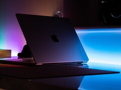 En halvöppen MacBook i ett mörkt rum, där ljus strömmar ut genom springan och faller på skrivbordet