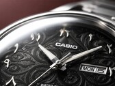 Närbild av Casio MTP-E735AR:s svarta urtavla med ett intrikat arabeskmönster, upphöjda östarabiska siffror, polerade silverfärgade visare och en dag- och datumvisning vid klockan 3.