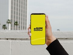 En hand som håller en smartphone med ordet eSIM i stor stil på en gul skärm.