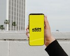 En hand som håller en smartphone med ordet eSIM i stor stil på en gul skärm.