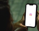 Kvinna som håller en smartphone i båda händerna, skärmen visar Instagrams startskärm