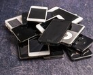 En hög med uttjänta smartphones på en grå yta