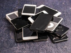 En hög med uttjänta smartphones på en grå yta