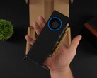 En person håller i Intel Arc Pro B50 lågprofils GPU för arbetsstationer med en fläktliknande kylare, mot dess förpackningslåda. (Bildkälla: ETA Prime via YouTube)