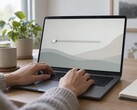 Händer på ett bärbart datortangentbord, en skjutreglage längst till vänster på skärmen
