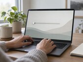 Händer på ett bärbart datortangentbord, en skjutreglage längst till vänster på skärmen