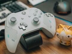 Vit Xbox-kontroll vilar på ett träbord bredvid en liten kattfigur (Bildkälla: FOX ^.ᆽ.^= ∫ via Pexels)