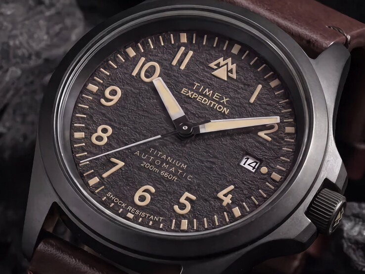 Närbild på Timex Expedition Field Post Titaniums strukturerade svarta urtavla med arabiska siffror, självlysande visare och markörer samt datumfönster.